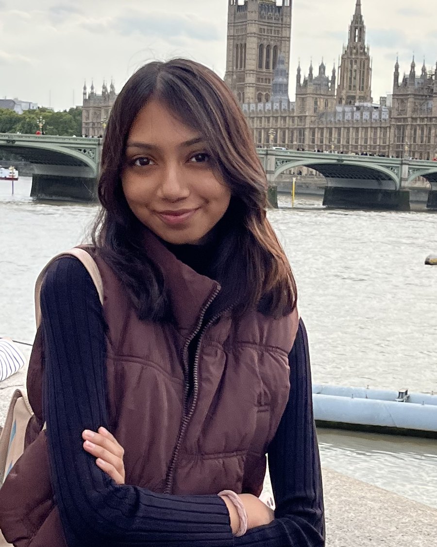 Muskaan Verma standing by the Thames, Westminster Bridge and the Houses of Parliament behind her